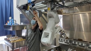 A technician makes an adjustment to a robot at Miso Robotics' White Castle test kitchen in Pasadena, California, July 9, 2020. Robots that can flip burgers, make salads and even bake bread are in growing demand as virus-wary kitchens try to put some distance between workers and customers.