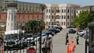 In this July 9, 2020, file photo, a correctional officer closes the main gate at San Quentin State Prison in San Quentin, California.