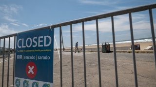 A pedestrian walks through a closed parking lot at Ocean Beach in San Francisco, April 30, 2020.