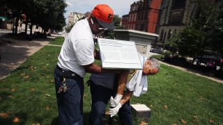 City workers remove a plaque near the pedestal that was formerly the base for a statue of Roger B. Taney, former Chief Justice of the U.S. Supreme Court and majority author of the Dred Scott decision, August 16, 2017 in Baltimore, Maryland.