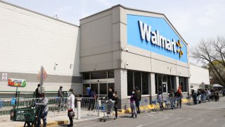 Las personas que usan máscaras y guantes esperan para ingresar a Walmart el 17 de abril de 2020 en Uniondale, Nueva York