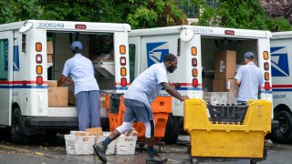 letter carriers load mail trucks for deliveries at a U.S. Postal Service facility