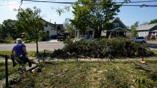 A woman hauls branches from a neighbor's yard to the street, Friday, Aug. 14, 2020, in Cedar Rapids, Iowa.