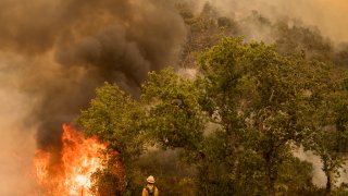 A firefighter from Santa Barbara County Fire watches a backburn just lit on Buck Mountain to fight the Carmel Fire near Carmel Valley, Calif., Wednesday, Aug. 19, 2020.