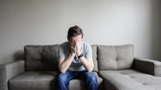 Depressed mature man sitting on couch.