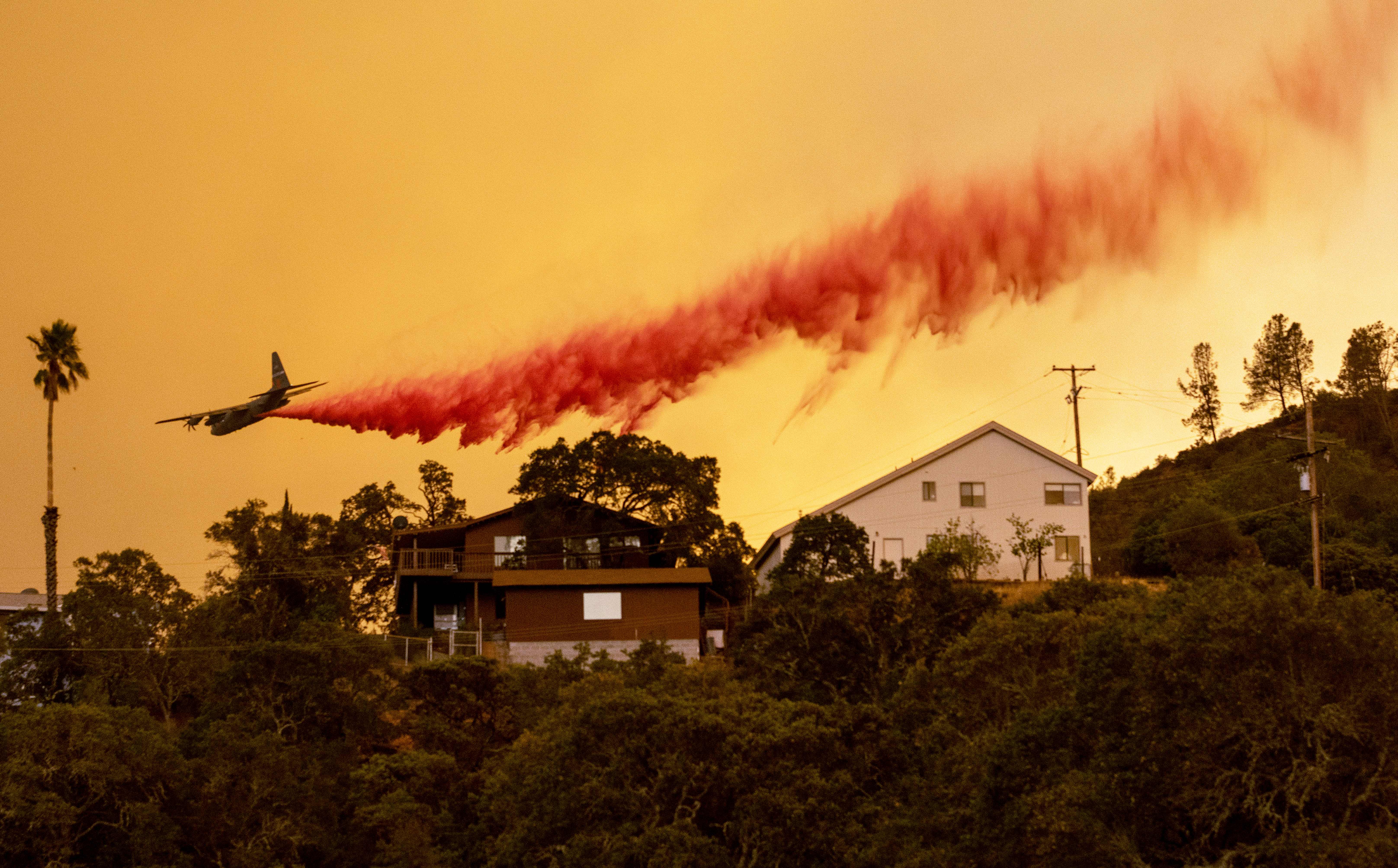 TOPSHOT – An airplane drops fire retardant over homes in the Spanish Flat area of Napa, California as flames rage through on August 18, 2020. – As of the late hours of August 18, the Hennessey fire has merged with at least 7 fires and is now called the LNU Lightning Complex fires. Dozens of fires are burning out of control throughout Northern California as fire resources are spread thin. (Photo by JOSH EDELSON / AFP) (Photo by JOSH EDELSON/AFP via Getty Images)