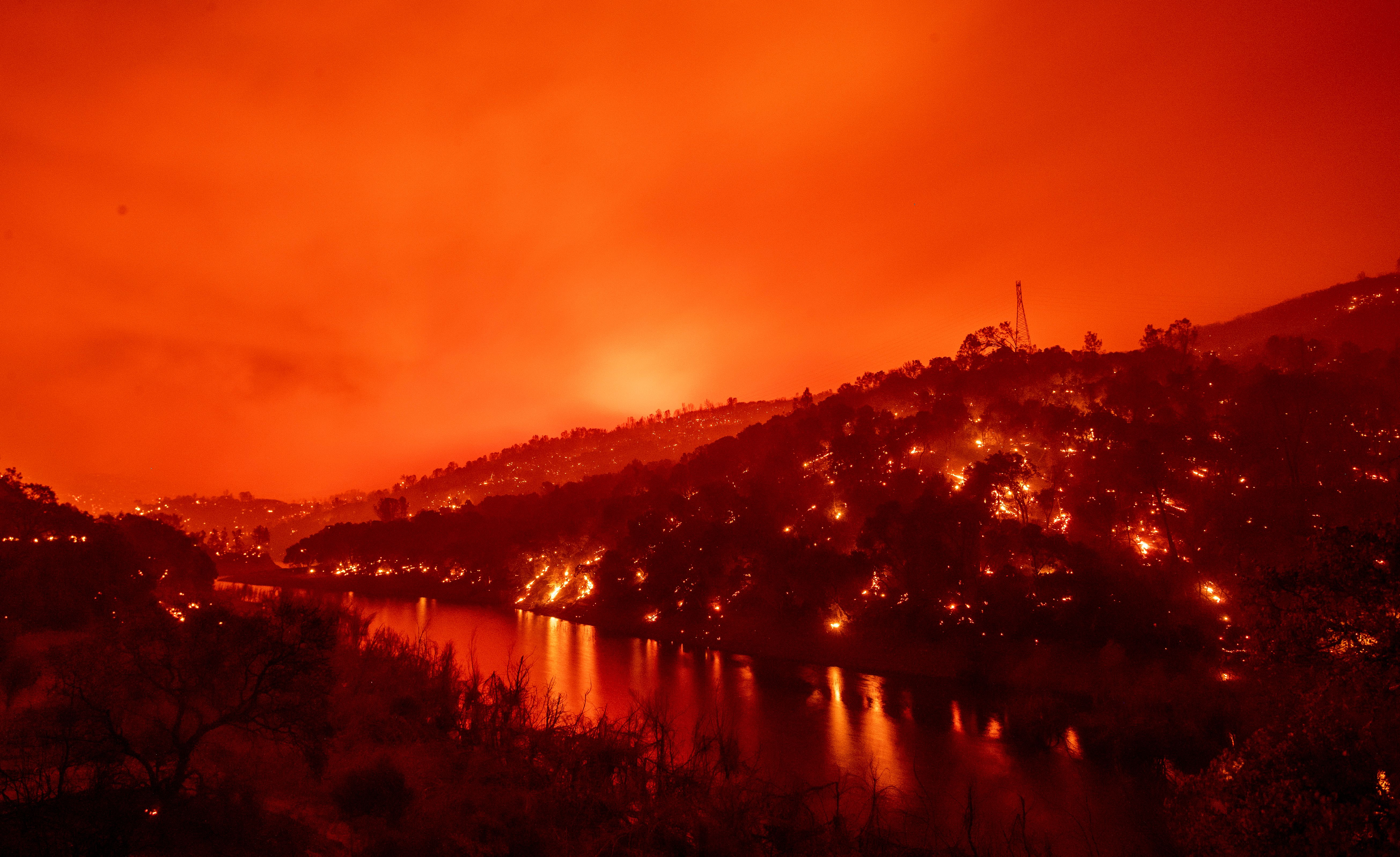 In this long exposure photograph, flames set ablaze both sides of a segment of Lake Berryessa during the Hennessey fire in the Spanish Flat area of Napa, California on August 18, 2020. – As of the late hours of August 18, the Hennessey fire has merged with at least 7 fires and is now called the LNU Lightning Complex fires. Dozens of fires are burning out of control throughout Northern California as fire resources are spread thin. (Photo by JOSH EDELSON / AFP) (Photo by JOSH EDELSON/AFP via Getty Images)