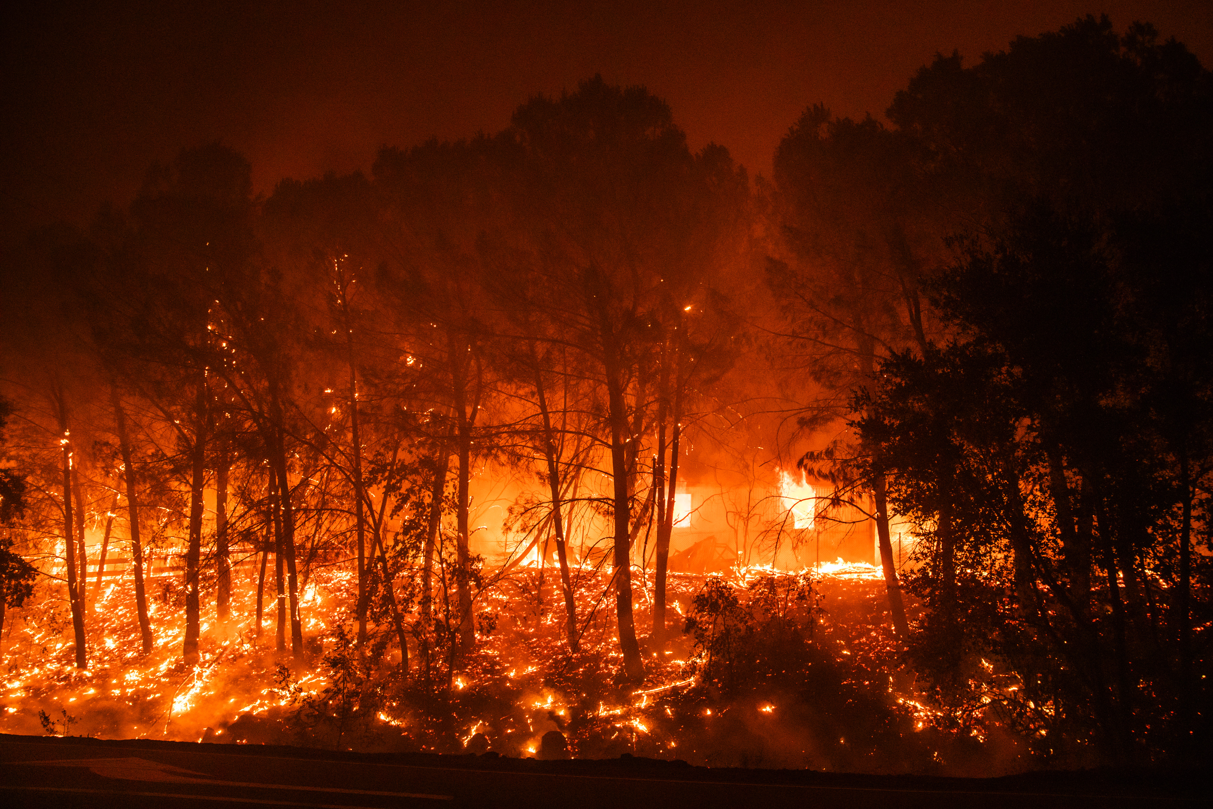 Trees burn near a structure during the Hennessey fire in Napa County, California, U.S., on Tuesday, Aug. 18, 2020. More Northern Californians were chased out of their homes Tuesday by lightning-sparked wildfires that burned out of control in several counties amid a punishing heat wave that pushed temperatures into the triple digits, according to the San Francisco Chronicle. Photographer: Philip Pacheco/Bloomberg via Getty Images