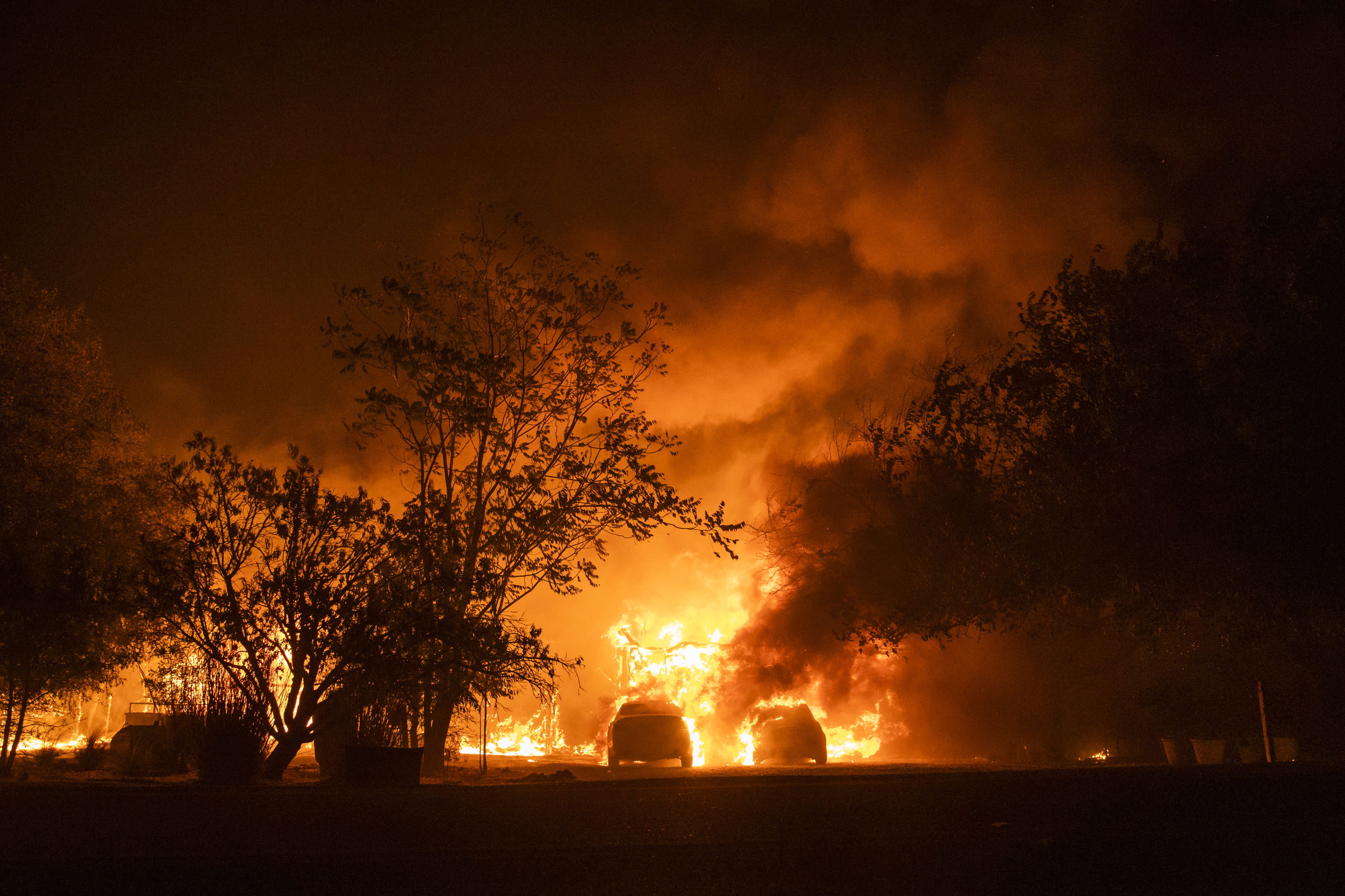 Vehicles catch fire in front of a burning home along Peaceful Glen Road during the Hennessy fire in Solano County, California, U.S., on Wednesday, Aug. 19, 2020. More Northern Californians were chased out of their homes by lightning-sparked wildfires that burned out of control in several counties amid a punishing heat wave that pushed temperatures into the triple digits. Photographer: Philip Pacheco/Bloomberg via Getty Images