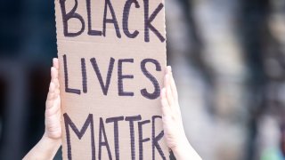 A protester holds a sign over their head that says BLACK LIVES MATTER.