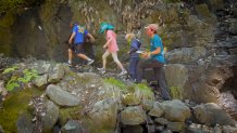 three kids and a teacher hiking over rocks