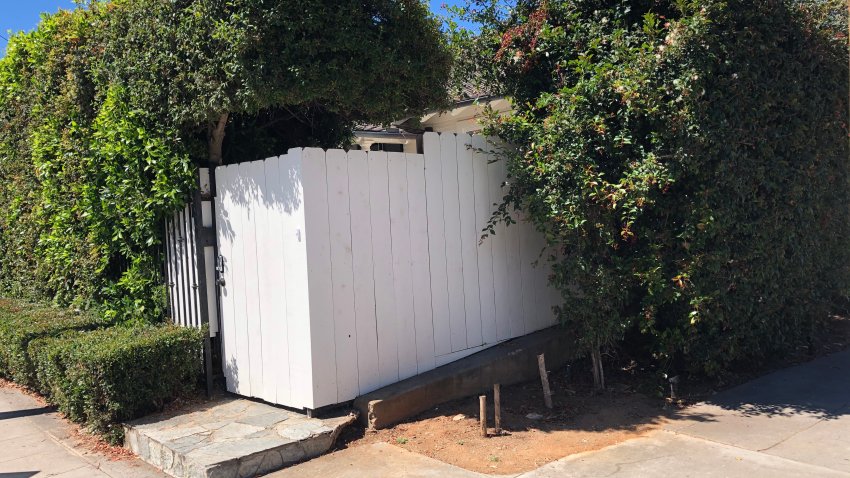 White Fence and large shrubs surround Banker's Hill home