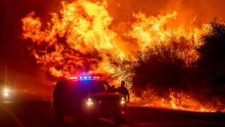 Flames lick above vehicles on Highway 162 as the Bear Fire burns in Oroville, Calif., on Wednesday, Sept. 9, 2020. The blaze, part of the lightning-sparked North Complex, expanded at a critical rate of spread as winds buffeted the region.