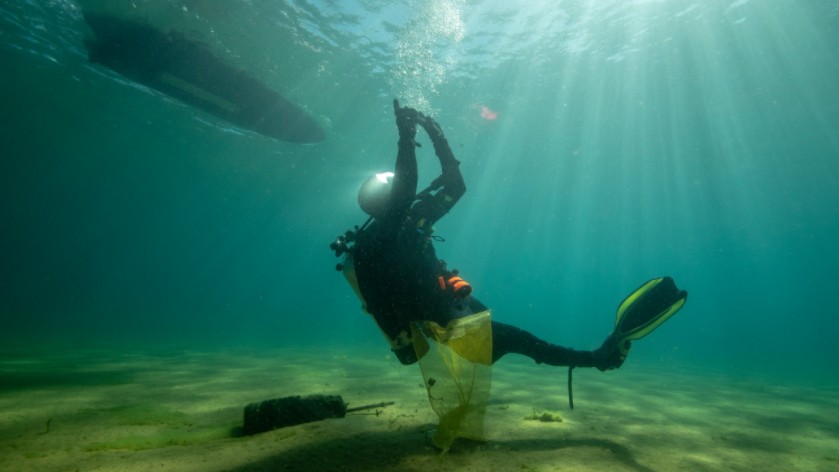 A diver uses hand signals to communicate with other members of the team.