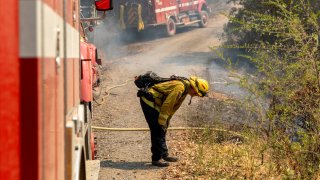 A firefighter leans over in an exhausted state.