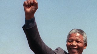 A picture taken on Sept. 5, 1990, shows anti-apartheid leader and African National Congress (ANC) member Nelson Mandela raising fist while addressing in Tokoza a crowd of residents from the Phola park squatter camp during his tour of townships.