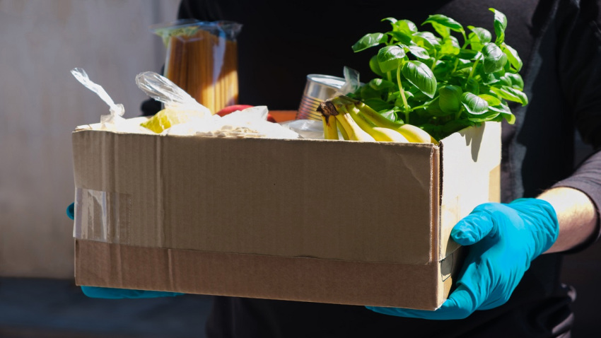 Home delivery during an epidemic. contactless delivery. Food donation. Men’s hands hold a box with products