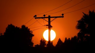 The sun sets behind power lines.