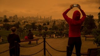 A person uses a mobile phone to take a photograph of smoke hanging over buildings in San Francisco, California, U.S., on Wednesday, Sept. 9, 2020. Powerful, dry winds are sweeping across Northern California for a third day, driving up the risk of wildfires in a region thats been battered by heat waves, freak lightning storms and dangerously poor air quality from blazes. Photographer: David Paul Morris/Bloomberg via Getty Images
