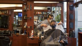 A customer gets a haircut from a stylist wearing a protective mask at a barber shop in San Francisco, California, U.S., on Tuesday, Sept. 15, 2020. Thousands of San Francisco businesses were allowed to reopen Monday following a nearly six-month shuttering, according to the San Francisco Chronicle. Photographer: David Paul Morris/Bloomberg via Getty Images