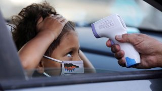 In this Sept. 2, 2020, file photo, a student receives a temperature check before leaving the car to enter STAR Eco Station Tutoring & Enrichment Center in Culver City, California.