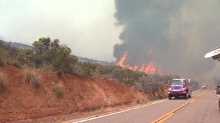 Flames are seen off the side of a road in the Japatul Valley area.