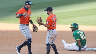 Jose Altuve of the Houston Astros high fives Carlos Correa while Marcus Semien of the Oakland Athletics sits on second base.