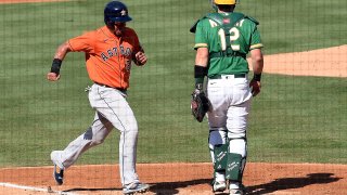 Michael Brantley of the Houston Astros scores a run against Sean Murphy of the Oakland Athletics.