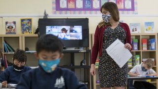 A teacher wearing a protective mask walks around the classroom during a lesson at an elementary school in San Francisco.