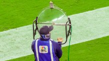 A man in an NBC Sports vest holds a large clear dish-shaped microphone