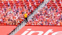 A lone stadium usher stands among rows of plastic fan cut-outs placed in empty seats