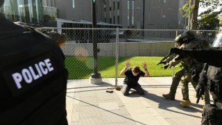 A man holds up his hands as he is taken into custody after fatally shooting another man in Denver, Colorado, on October 10, 2020. At the time two rallies, one right-wing and one left-wing, were taking place near one another. The man who died was participating in the right-wing rally. Denver Channel 9News has confirmed that the man who did the shooting was a private security guard contracted by them and is in custody after the shooting. It has been confirmed the guard was contracted through Pinkerton for the station.