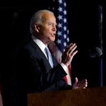 Joe Biden speaks with American flags in background