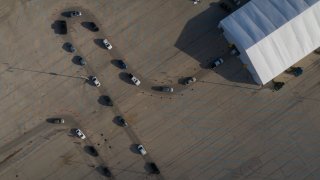 People in vehicles wait in line to enter a drive-thru COVID-19 testing site