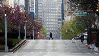 A man, with a face mask, crosses a street on Park Avenue, remaining nearly empty due to coronavirus (COVID-19) pandemic in New York City, United States, on April 12, 2020.