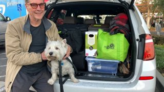 Matt Frinzi, 68, poses with his dog, Whitey, and his car filled with his belongings, in West Sacramento, California, on Tuesday, Dec. 15, 2020. Prinzi has lived in California for 25 years. But Tuesday he officially moved to Reno, Nevada. He said his quality of life has deteriorated so much in California that he wanted to leave.