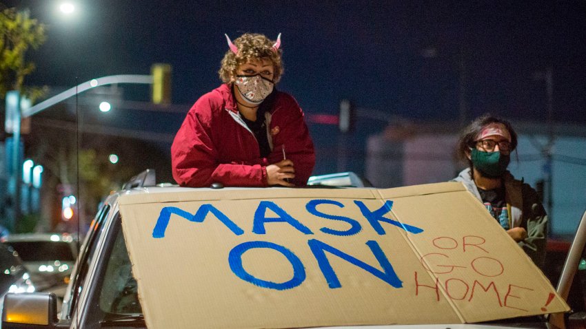 Protesters wearing face masks stand on their vehicle.