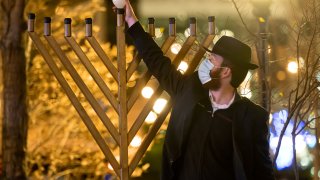 A member of Chabad of Midtown lights the first candle of Hanukkah in the Hudson Yards on December 10, 2020 in New York City