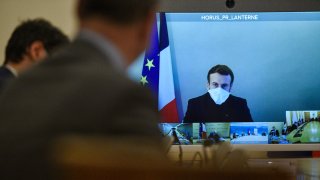 French President Emmanuel Macron is seen on a screen from his presidential residence in Versailles as he attends by video conference the weekly cabinet meeting at the Elysee Palace in Paris, Monday, Dec. 21, 2020.