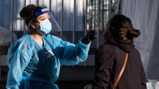 A healthcare worker administers a test at a Covid-19 testing tent outside a Bay Area Rapid Transit (BART) station.