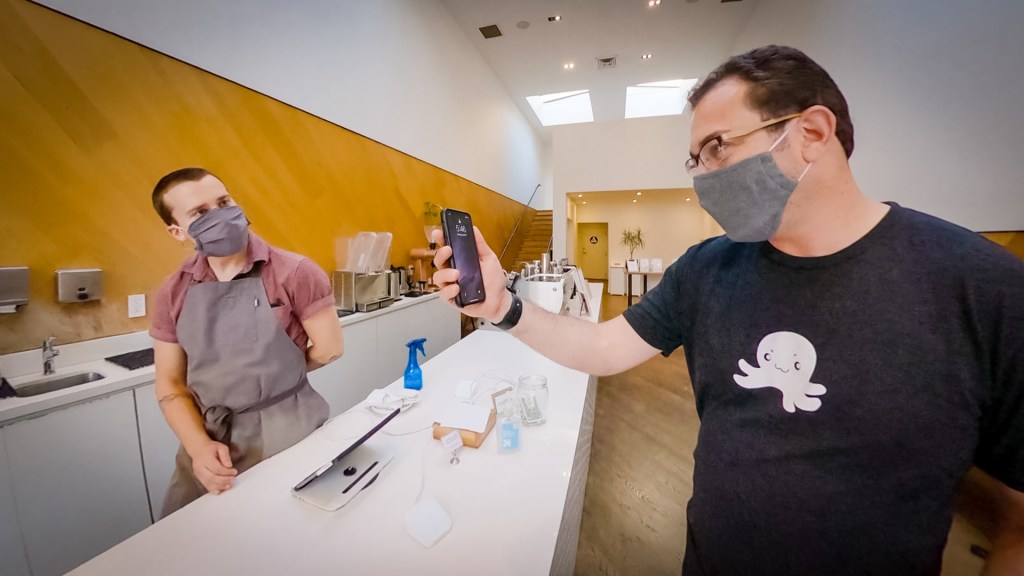 two men in masks converse across a counter