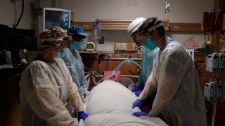 FILE – In this Dec. 22, 2020, file photo, medical workers prepare to manually prone a COVID-19 patient in an intensive care unit at Providence Holy Cross Medical Center in the Mission Hills section of Los Angeles.