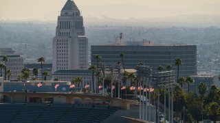 Flags fly half-mast at Dodgers Stadium in honor of the recent passing of the Hall of Fame manager Tommy Lasorda overlooking Los Angeles City Hall, Jan. 11, 2021. Dodger Stadium, the home stadium of Major League Baseball's Los Angeles Dodgers holds 56,000 spectators. The The coronavirus death toll in California reached 30,000 on Monday, another staggering milestone as the nation's most populous state endures the worst surge of the nearly yearlong pandemic.