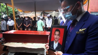 A colleague holds a portrait of Okky Bisma, a flight steward, one of victims of the crashed Sriwijaya Air passenger jet during his funeral in Jakarta, Indonesia.Thursday, Jan. 14, 2021. An aerial search for victims and wreckage of the crashed Indonesian plane expanded Thursday as divers continued combing the debris-littered seabed looking for the cockpit voice recorder from the lost Sriwijaya Air jet.