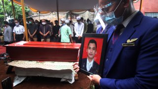 A colleague holds a portrait of Okky Bisma, a flight steward, one of victims of the crashed Sriwijaya Air passenger jet during his funeral in Jakarta, Indonesia.Thursday, Jan. 14, 2021. An aerial search for victims and wreckage of the crashed Indonesian plane expanded Thursday as divers continued combing the debris-littered seabed looking for the cockpit voice recorder from the lost Sriwijaya Air jet.