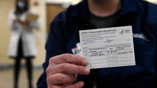 A Poudre Valley Hospital ICU Nurse shows off her vaccination card after getting the first round of Covid-19 vaccines at UC Health Poudre Valley Hospital on December 14, 2020 in Fort Collins, Colorado.