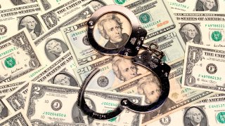 handcuffs sitting on top of a pile of us dollars of assorted denominations