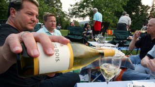 Michael Van Parks, left, pours wine with friends, Bill Beeman, center, and Don Usher, right, all of West Hartford, Conn., while having a picnic on the lawn at Tanglewood in Lenox, Mass