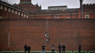 Members of the public pause to look at an artwork bearing the hallmarks of street artist Banksy