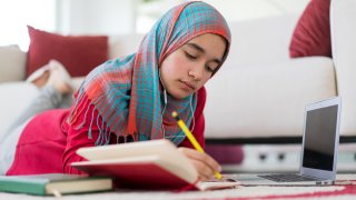Middle eastern teenage girl with hijab studying at home